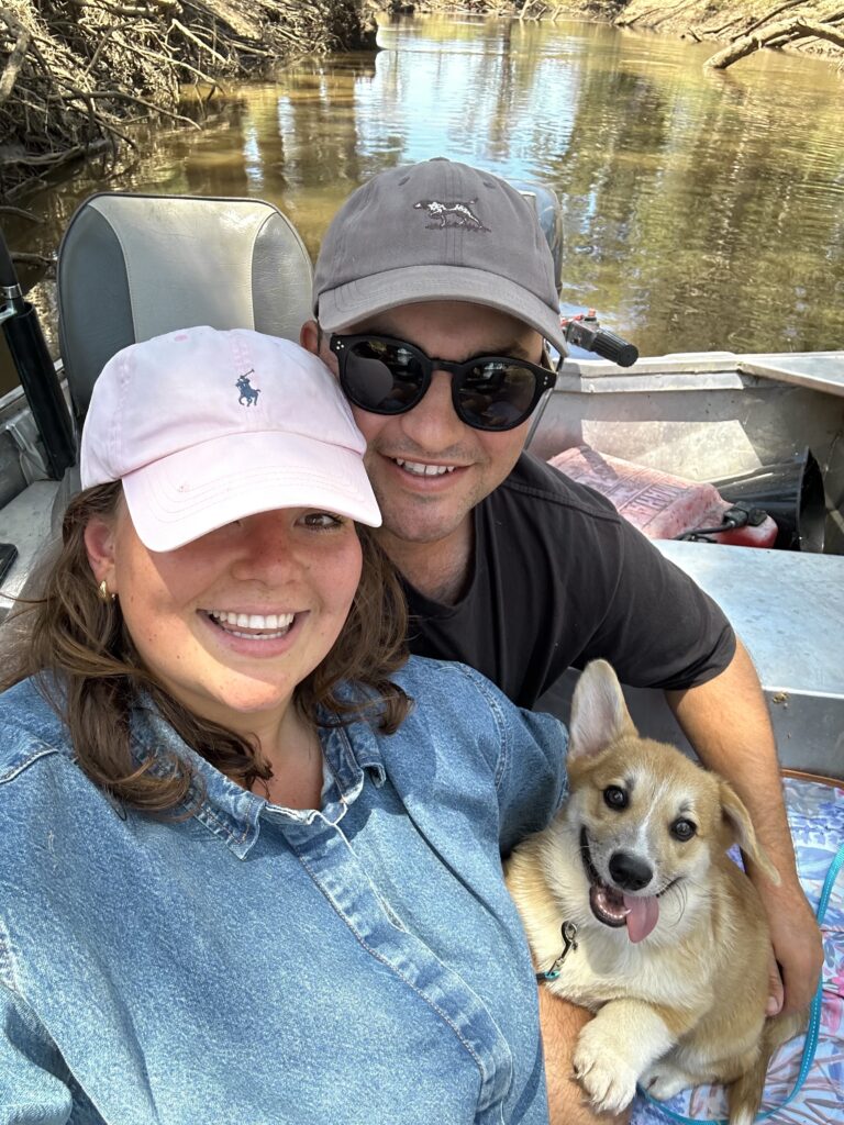 A happy couple with a corgi on a boat.