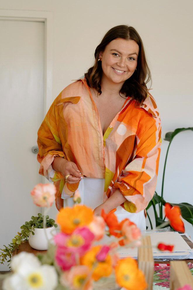 Smiling woman in a colourful shirt with flowers.
