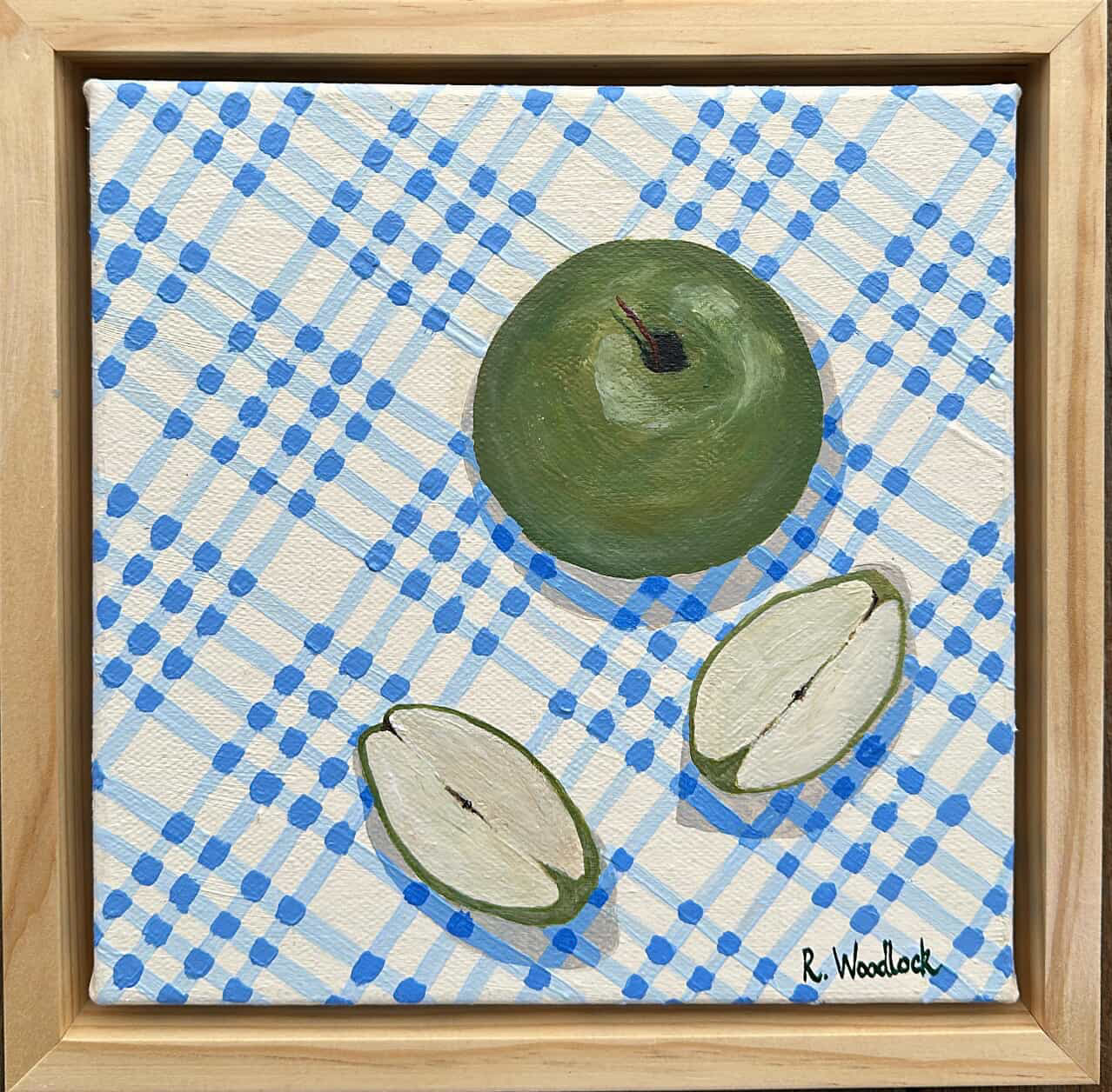 Green apple on blue checkered background with slices.