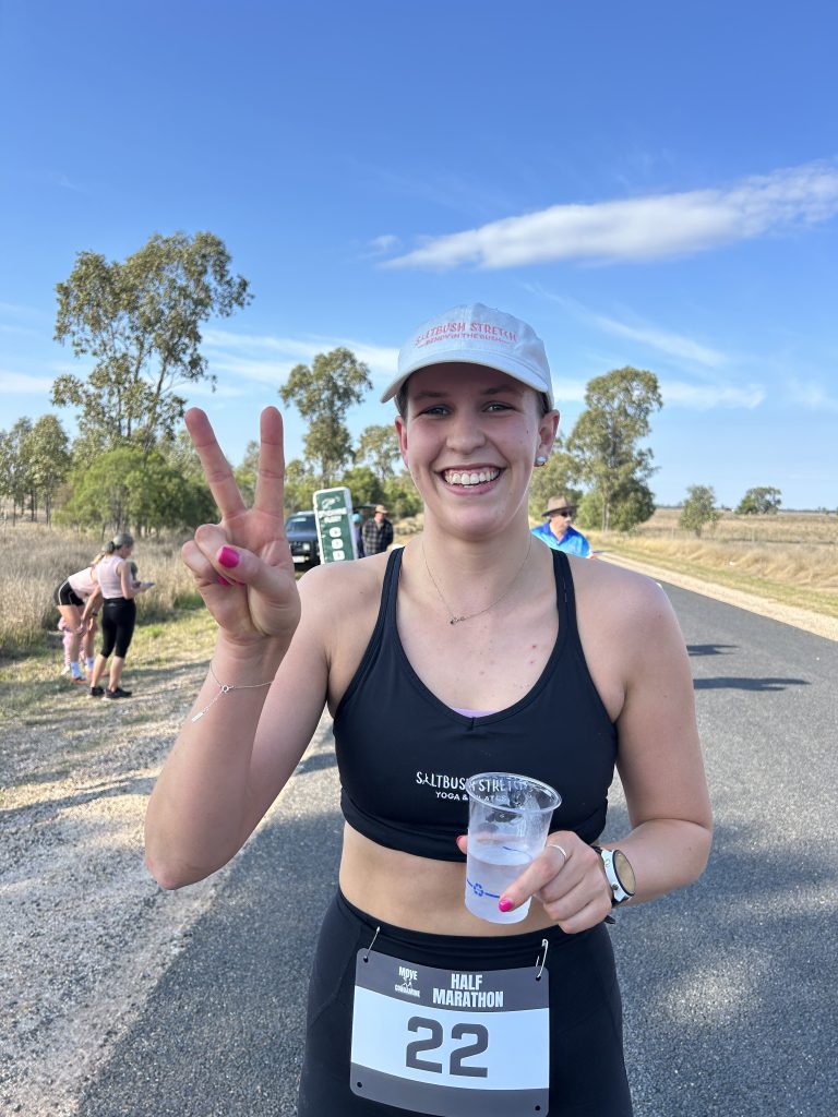 Smiling runner holding water cup and making peace sign.