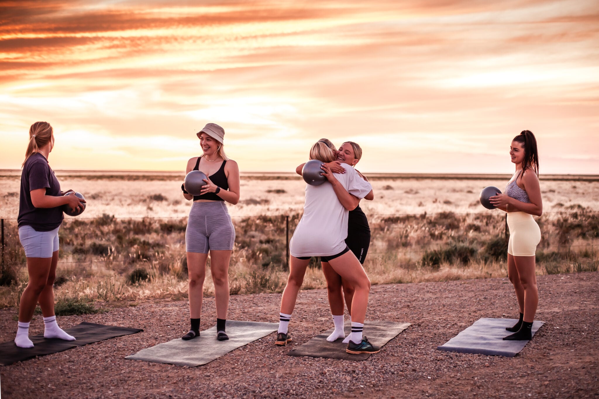 Women practising outdoor yoga at sunset on mats